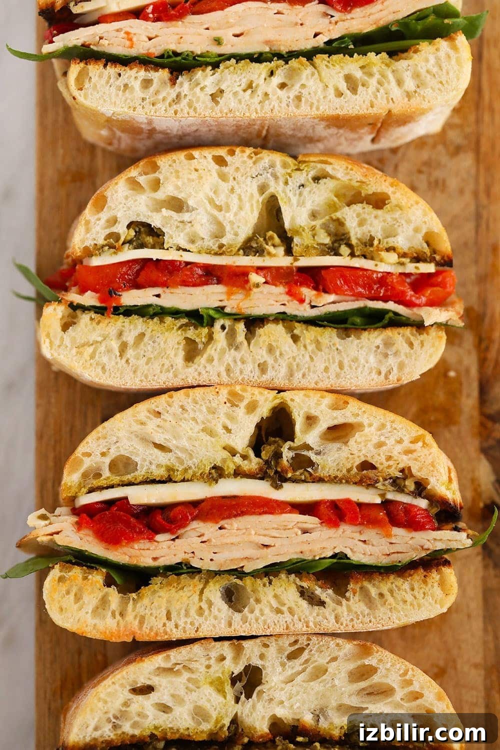Grilled Roasted Red Pepper, Pesto & Turkey Sandwich on a cutting board 