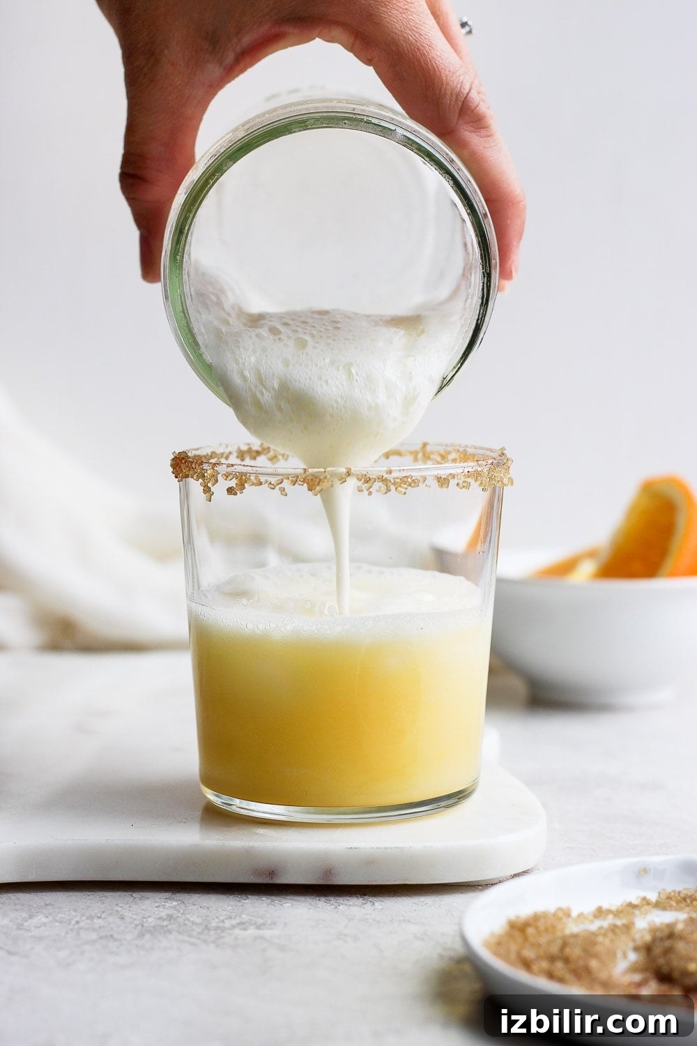 Frothy Orange Creamsicle Cocktail Recipe with Vanilla 5 Pouring froth into an orange cocktail