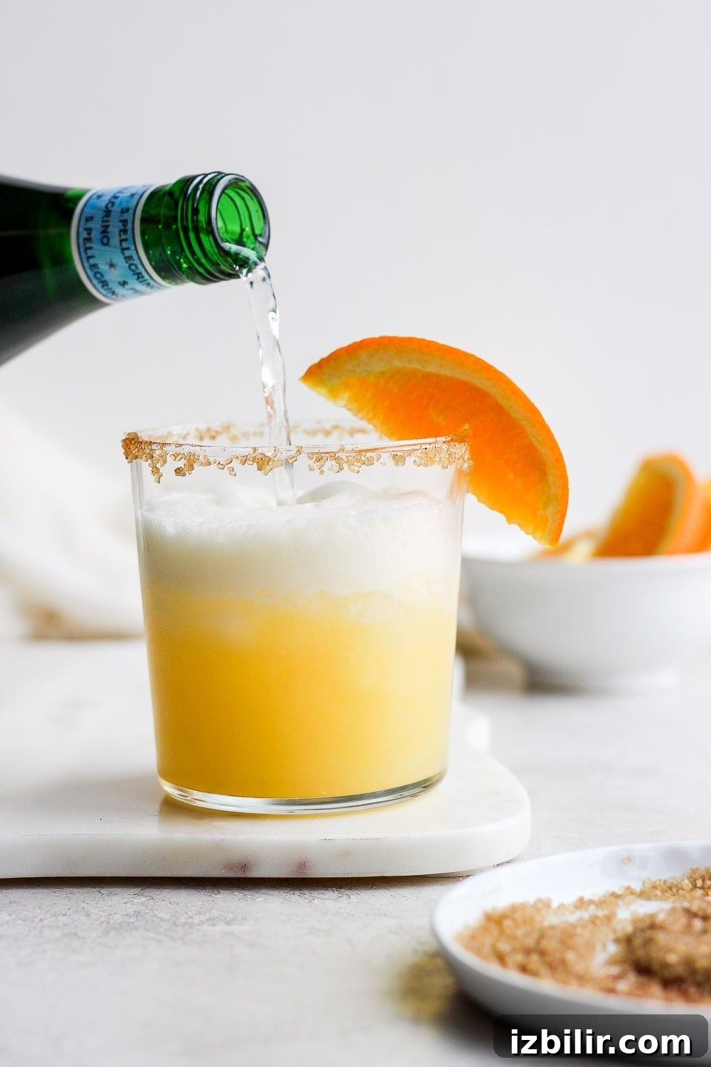 Frothy Orange Creamsicle Cocktail Recipe with Vanilla 6 Pouring bubbly water into the cocktail