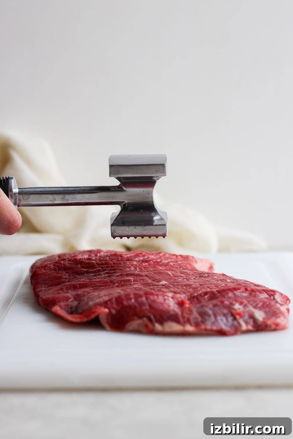 Pounding flank steak down to make it all the same thickness.