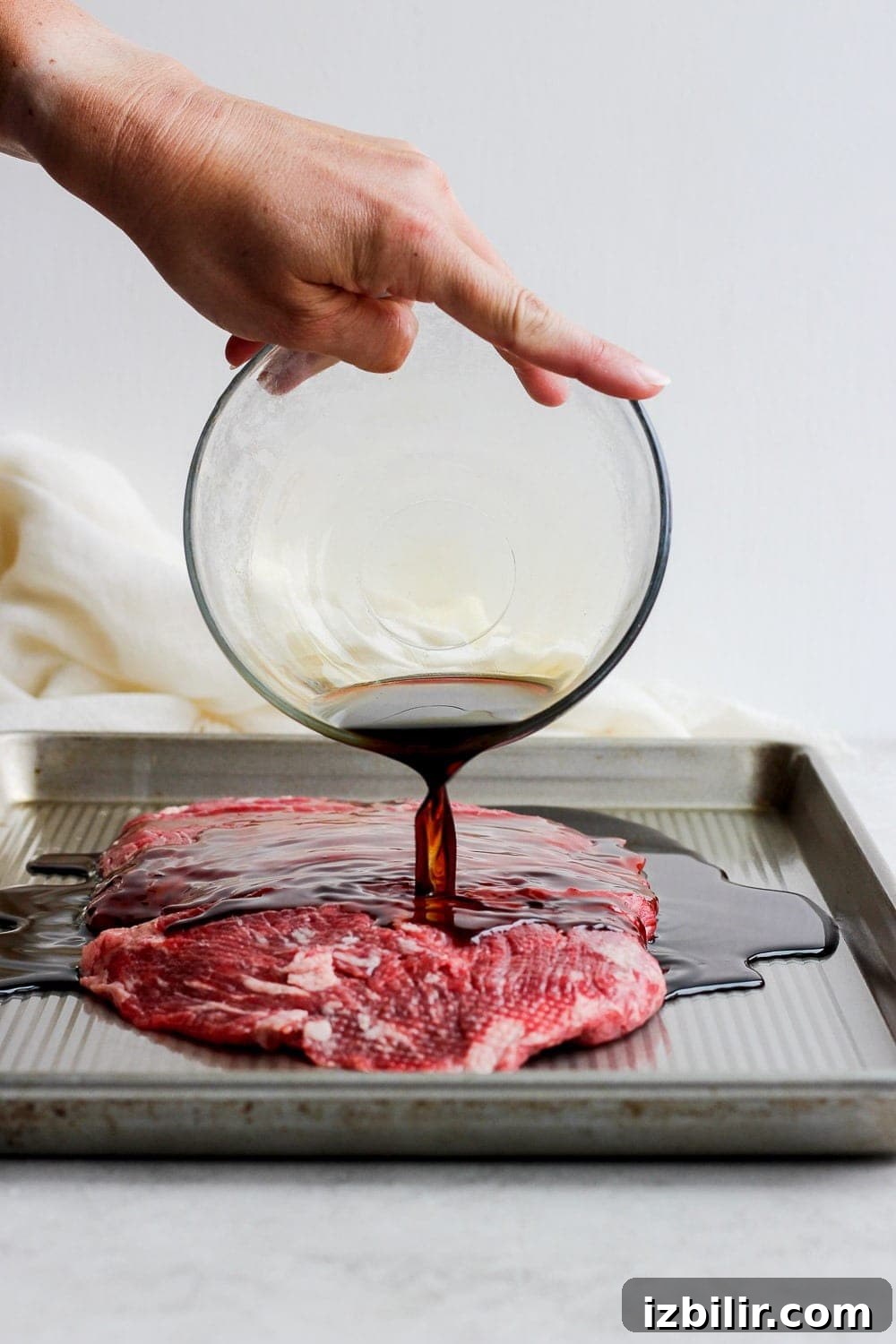 Pouring marinade over flank steak.