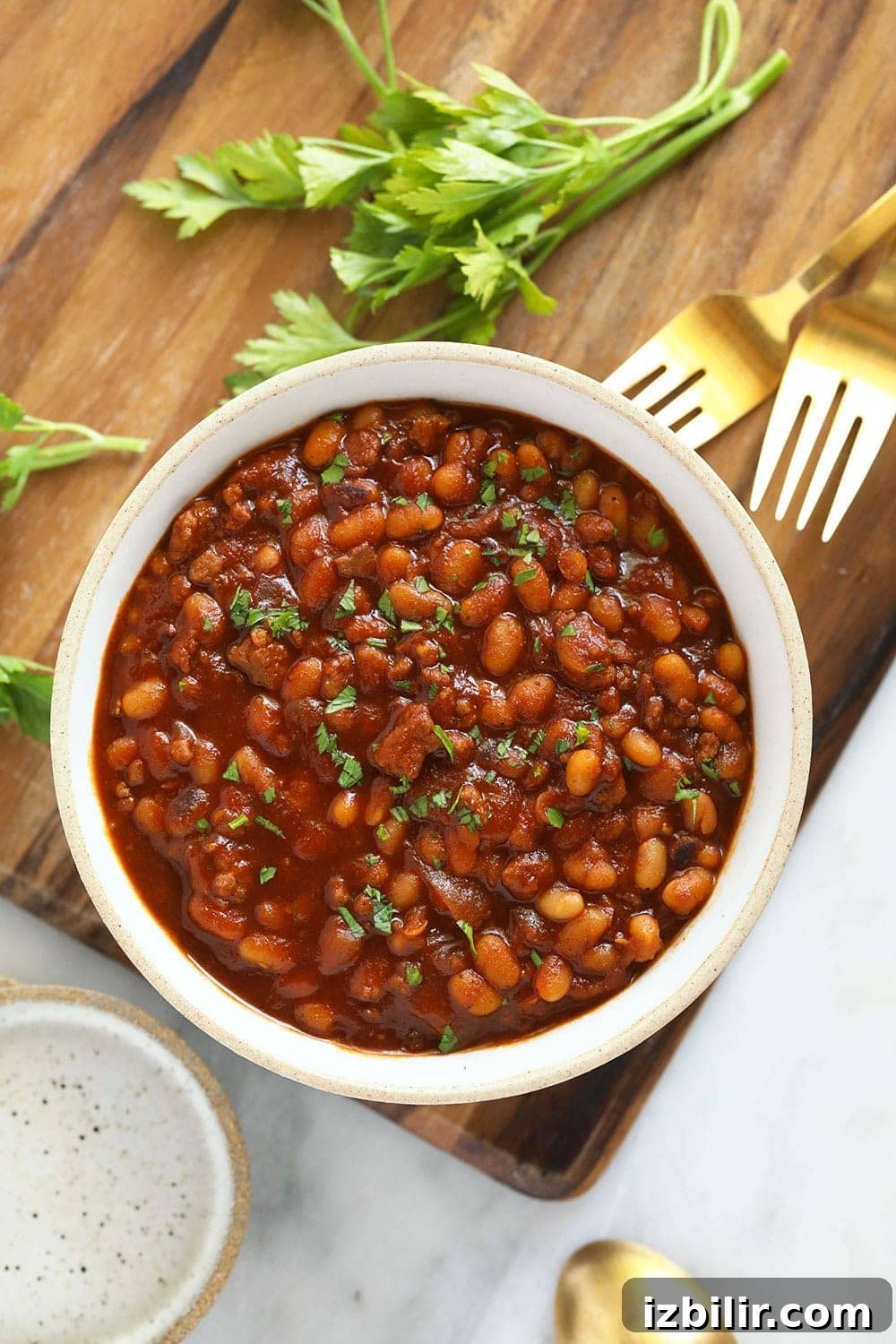 Instant Pot baked beans in a bowl topped with parsley.