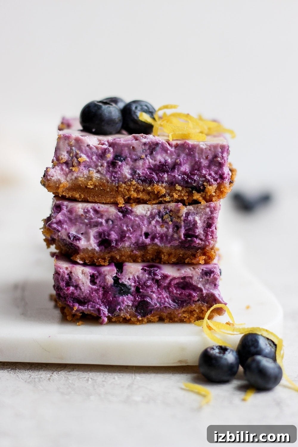 blueberry cheesecake bars stacked three high looking delicious and ready to eat.