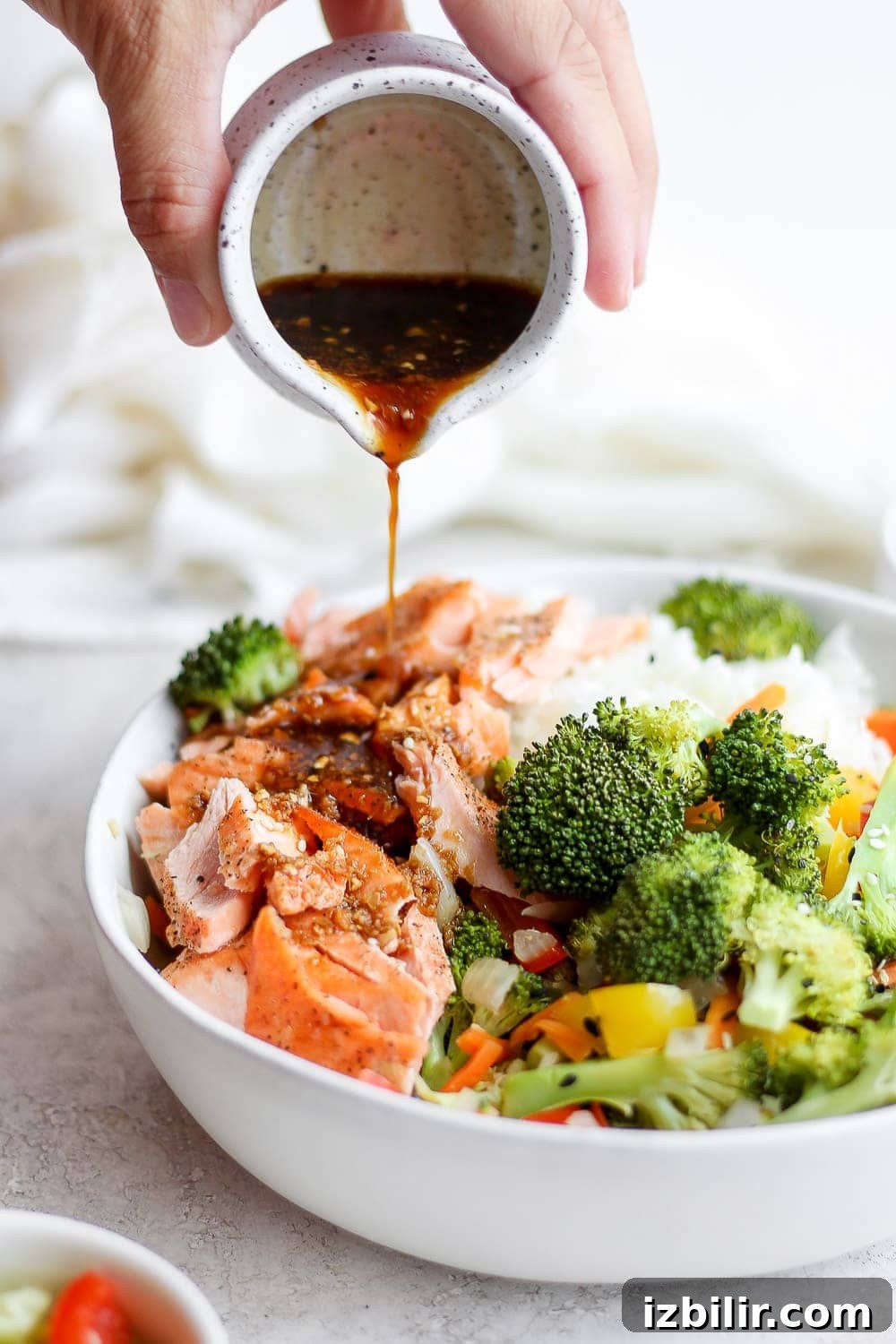 Sheet Pan Salmon Stir-Fry with Roasted Vegetables 6 sauce being poured over sheet pan salmon stir fry in a bowl