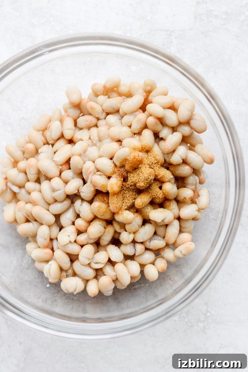 white navy beans and spices in a bowl ready to be mixed into shrimp salad