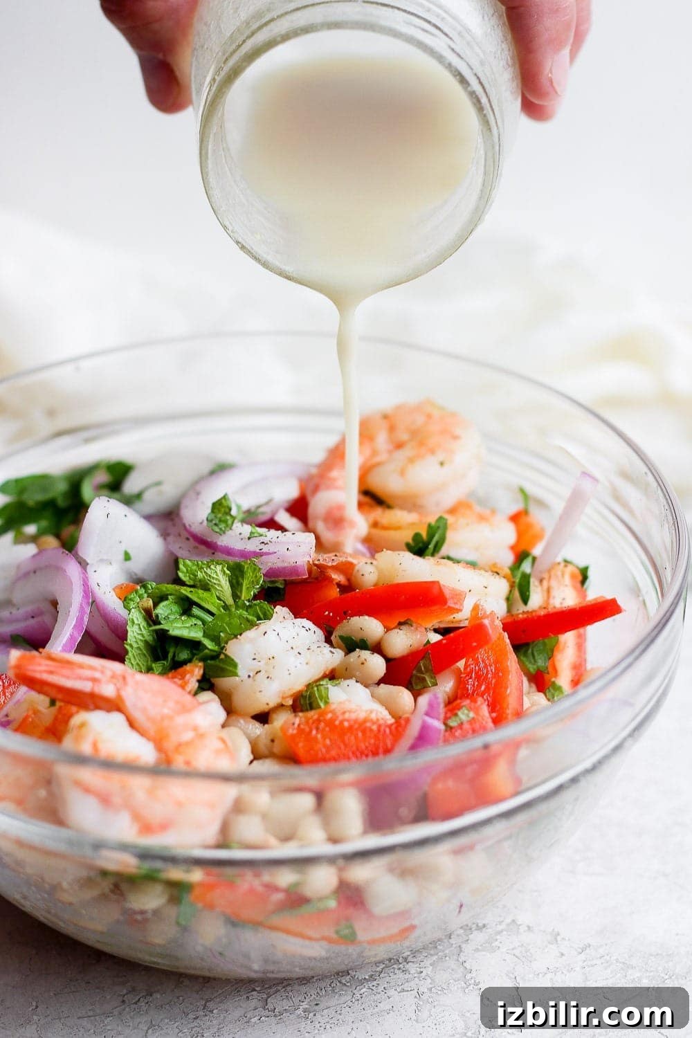 creamy dressing being poured over healthy shrimp salad