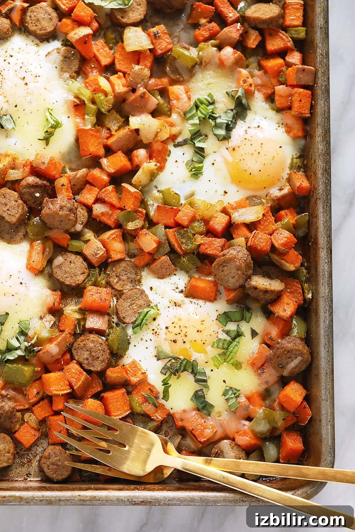 sweet potato hash on baking sheet with eggs and two forks