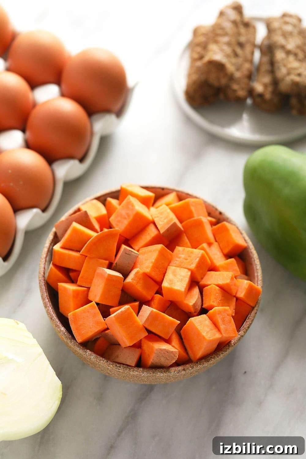 raw sweet potato, eggs, breakfast sausage, a pepper, and onion