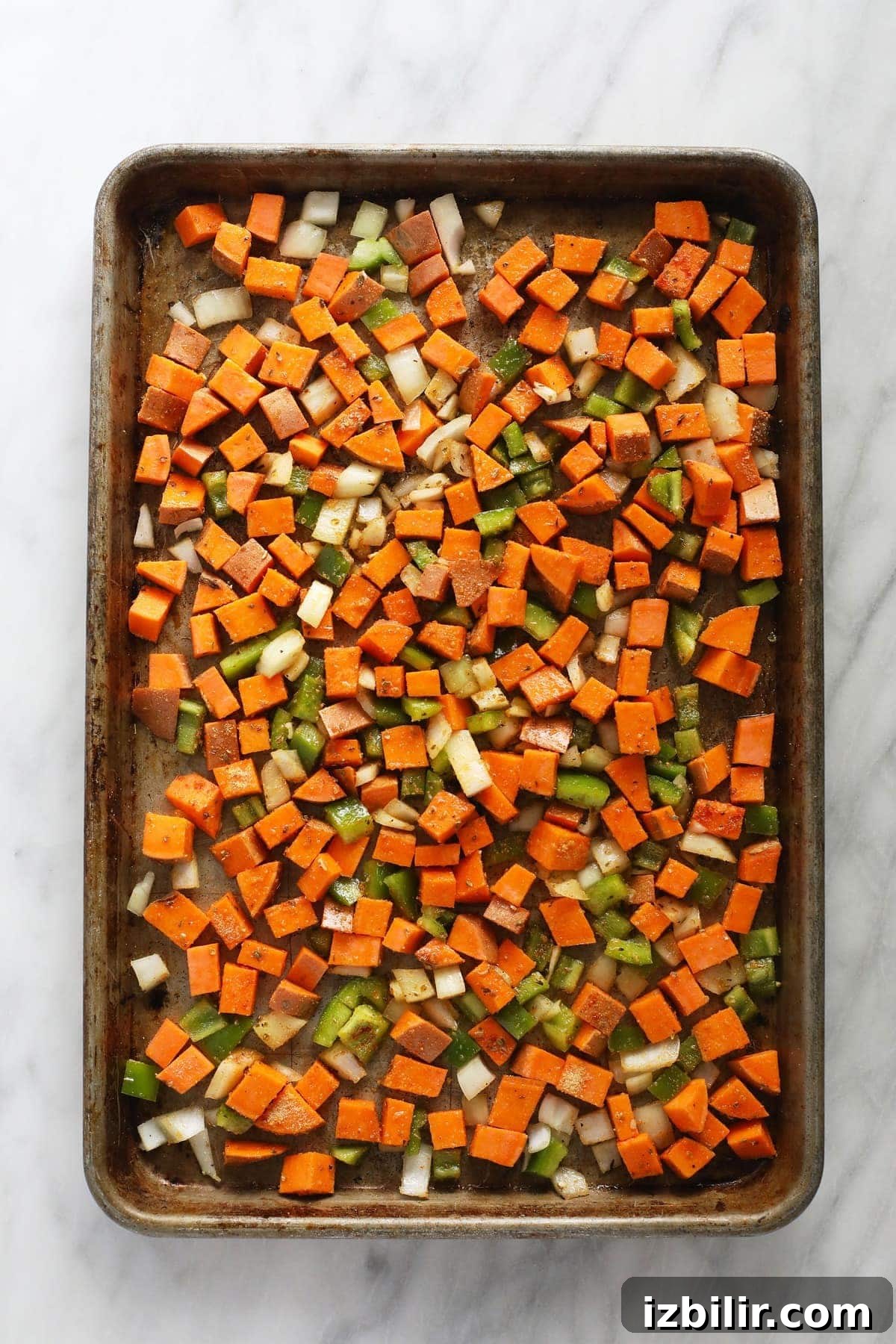 raw sweet potato, bell pepper, and onion on pan