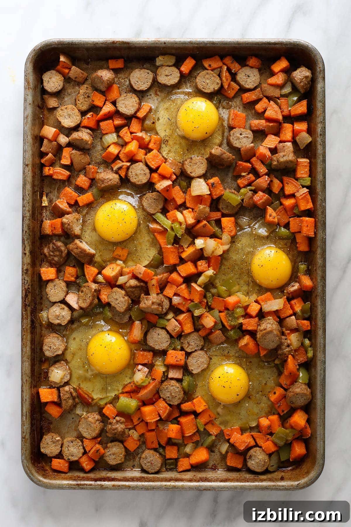 sweet potato nests with raw eggs cracked into them on sheet pan