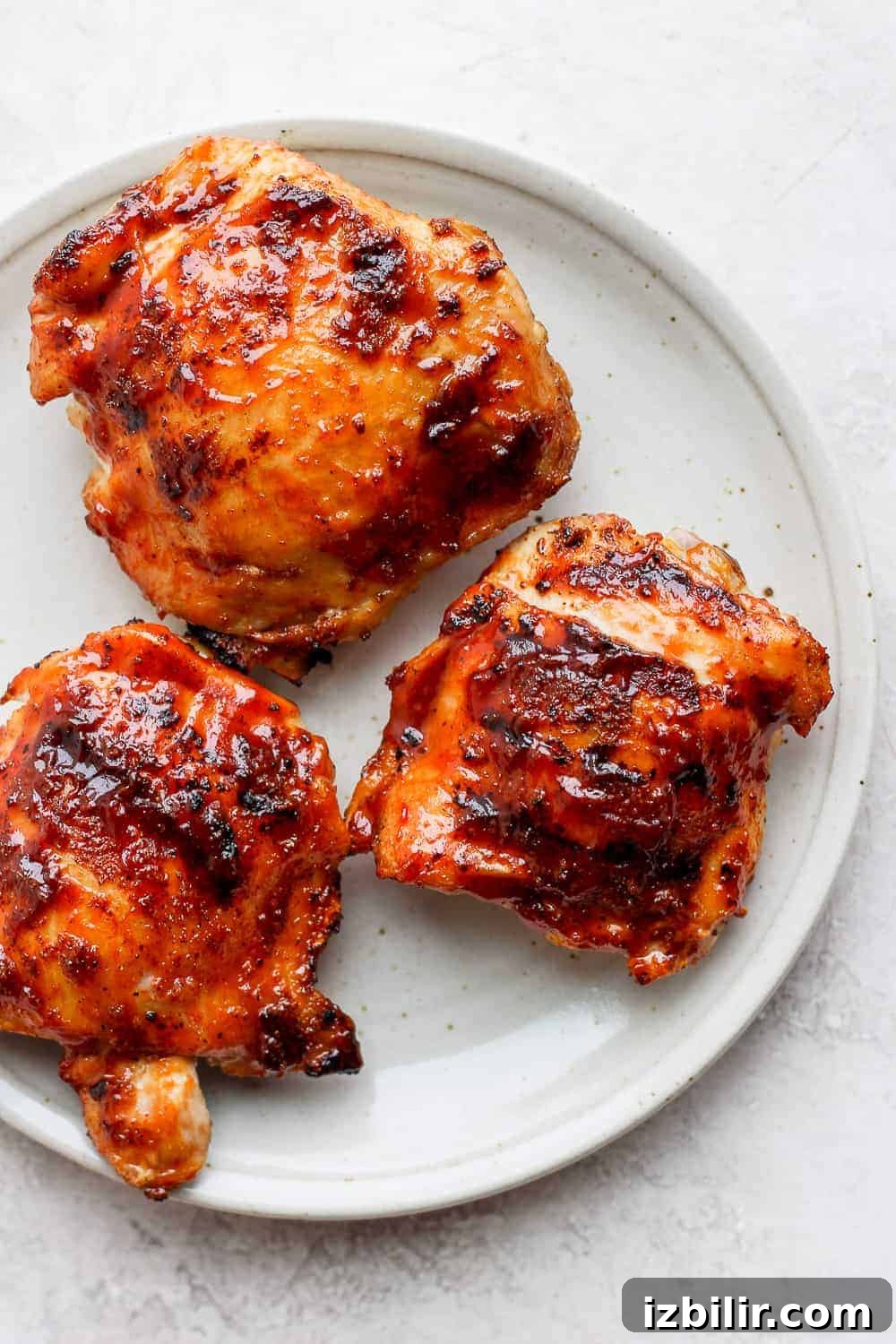 Three grilled chicken thighs on a plate