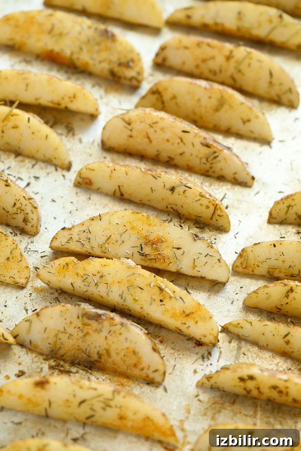 Baked potato wedges before they were baked with oil and herbs on a pan. 