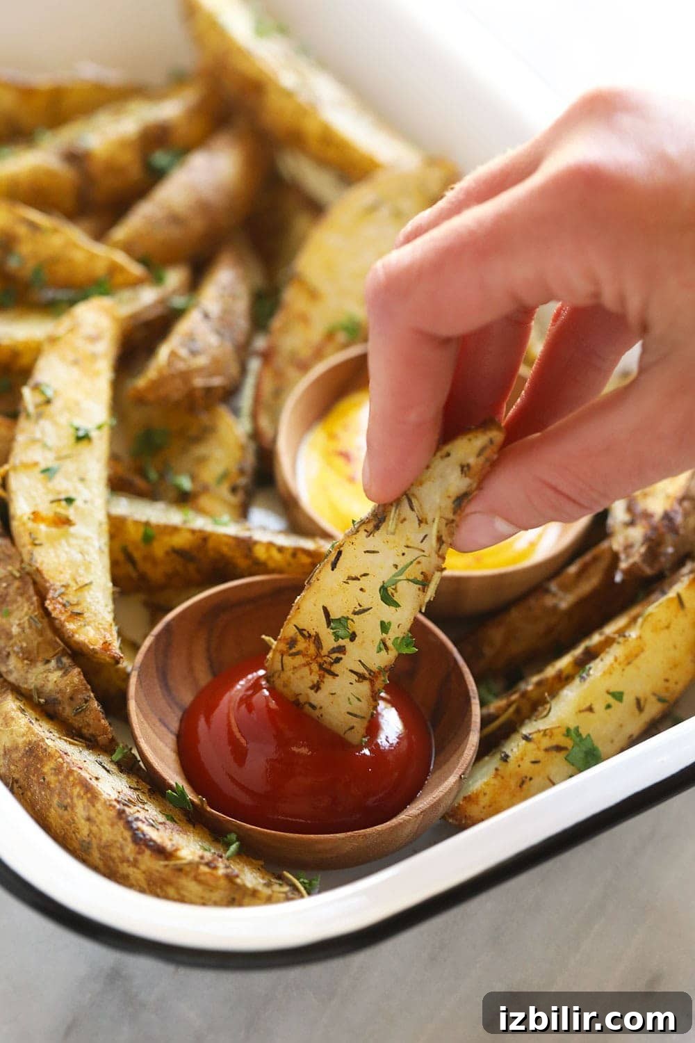 Dipping a potato wedge into ketchup.