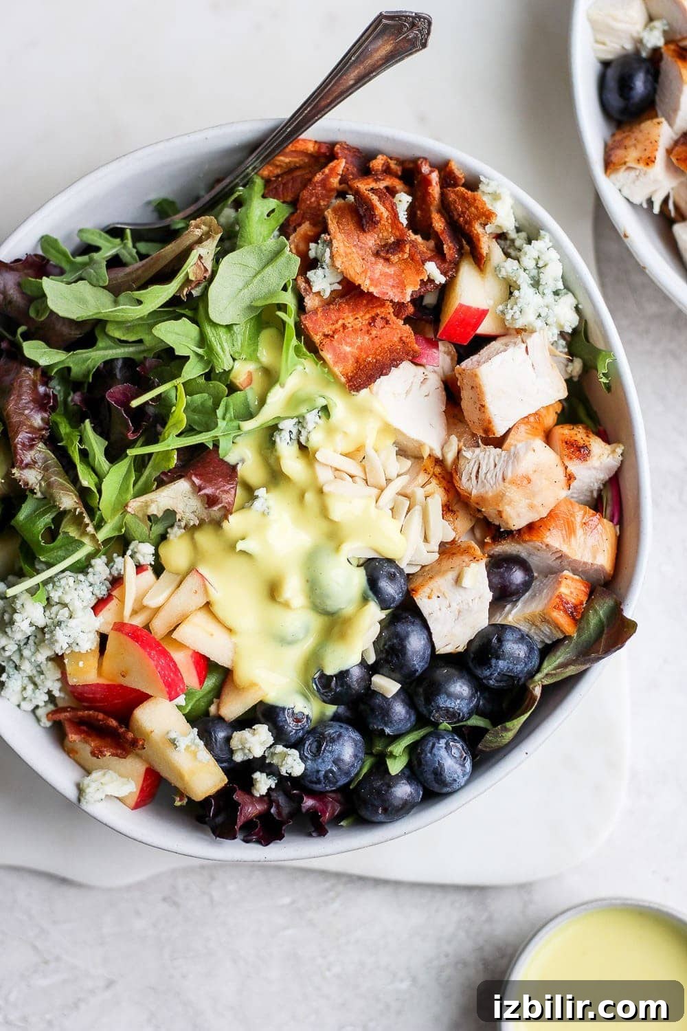 The most delicious grilled chicken salad! Grilled chicken salad in a bowl with a small cup of dressing.