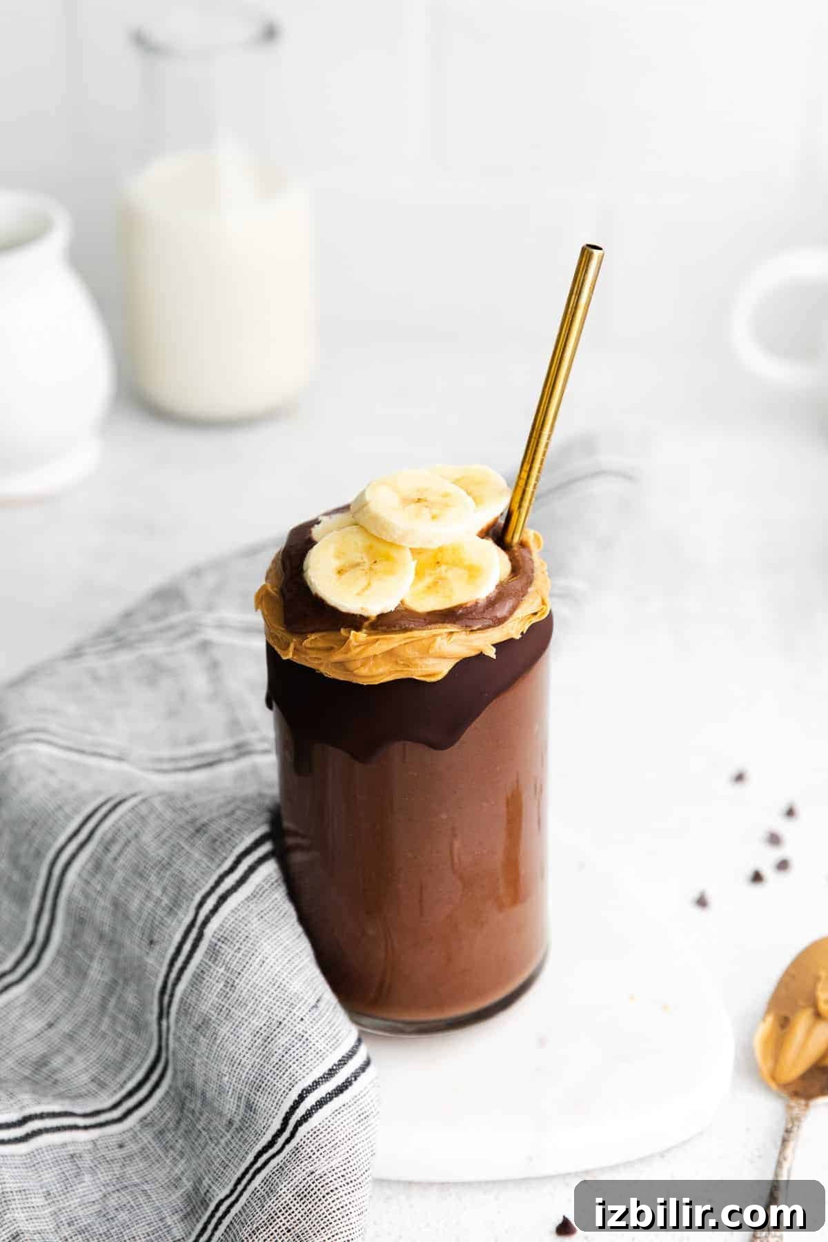 This Chocolate Peanut Butter Banana Smoothie is packed with protein and even has a full serving of greens in it. The best part is, it's healthy and tastes exactly like a peanut butter cup! smoothie topped with peanut butter and banana