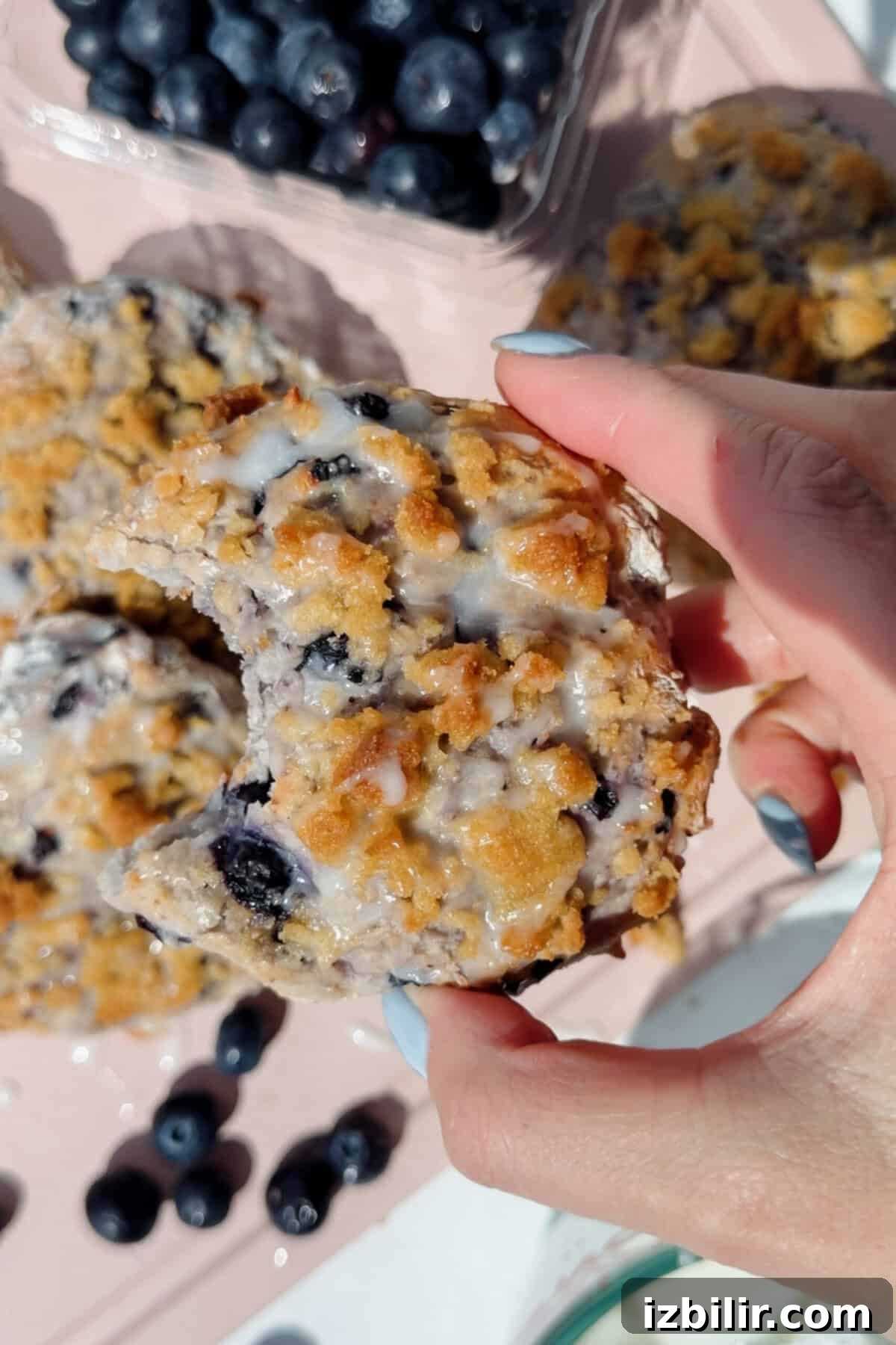 Buttery Blueberry Cottage Cheese Biscuits with Streusel 2 hand holding a blueberry cottage cheese biscuit with a bite taken out showing fluffy interior