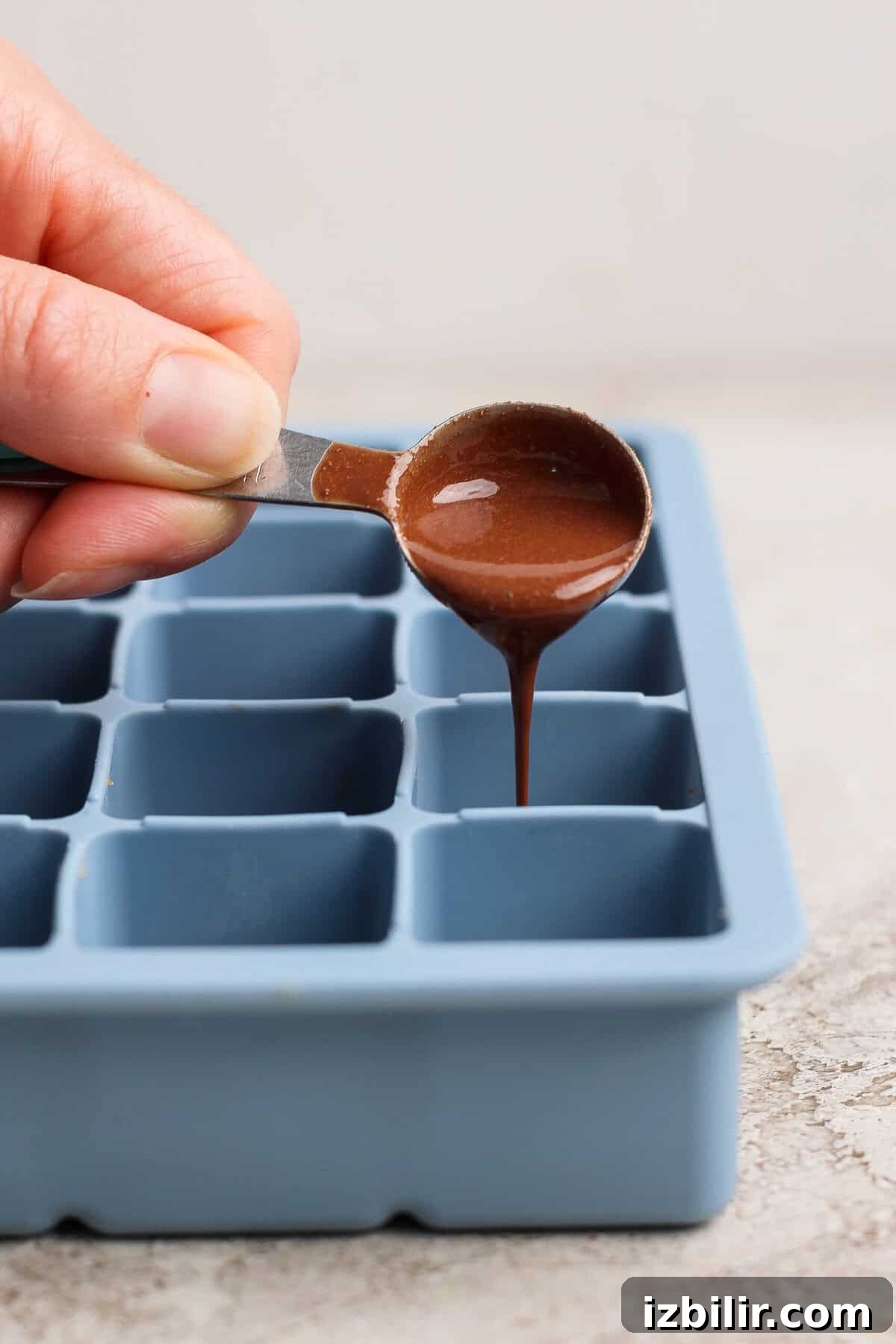 No-Bake Thin Mint Protein Bites Recipe 6 pouring melted peppermint chocolate over protein bite base in a silicone tray