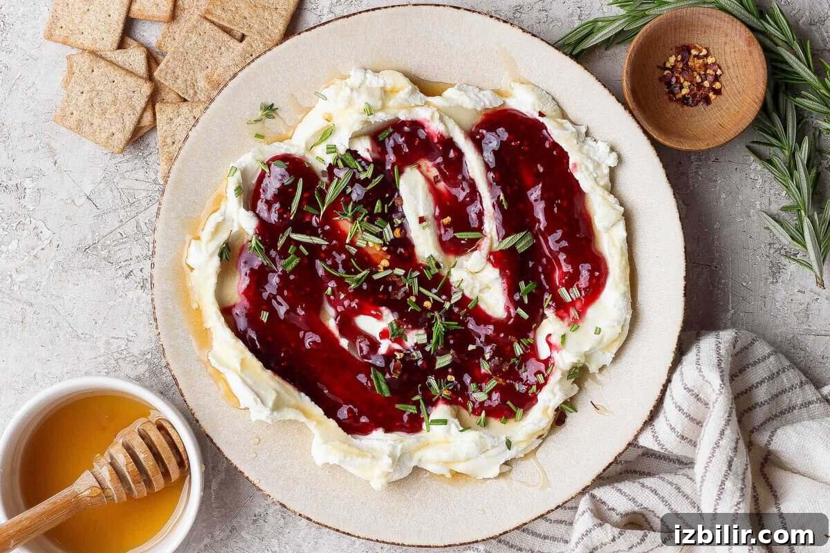 goat cheese dip topped with raspberry jam, fresh rosemary, and red pepper flakes served with crackers and hot honey