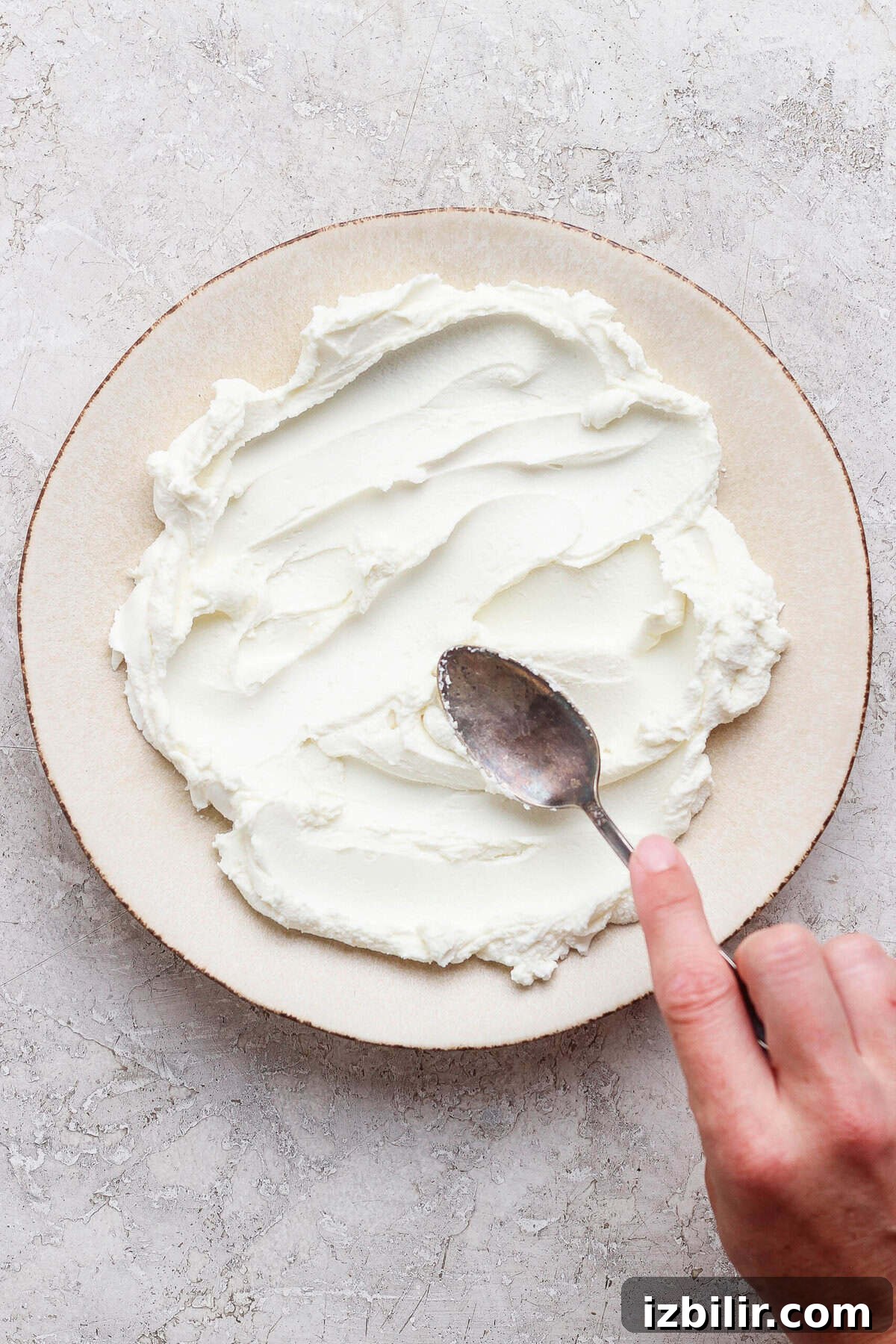 spreading goat cheese onto a plate with a spoon to make goat cheese dip