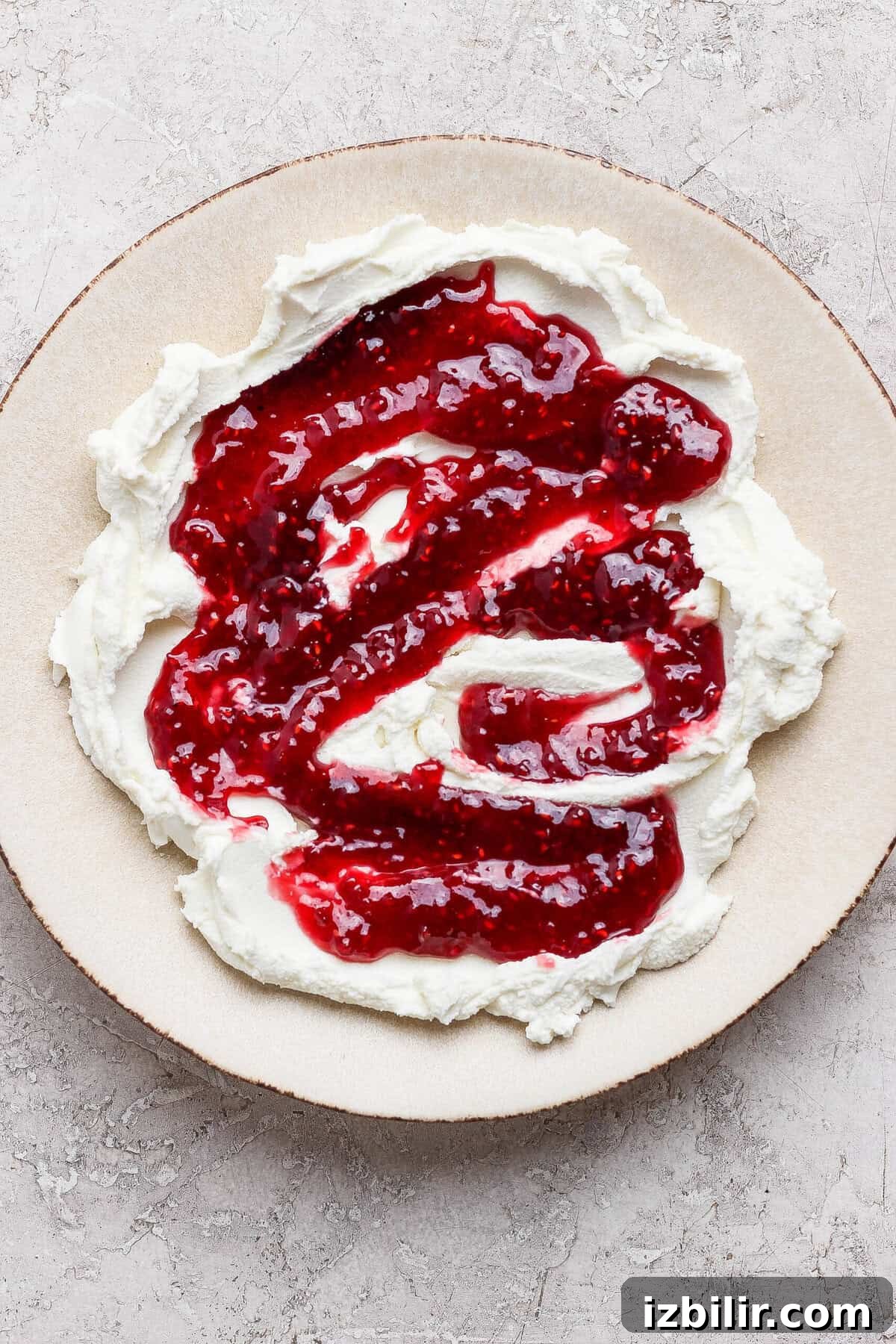 raspberry jam swirled over spread goat cheese on a plate