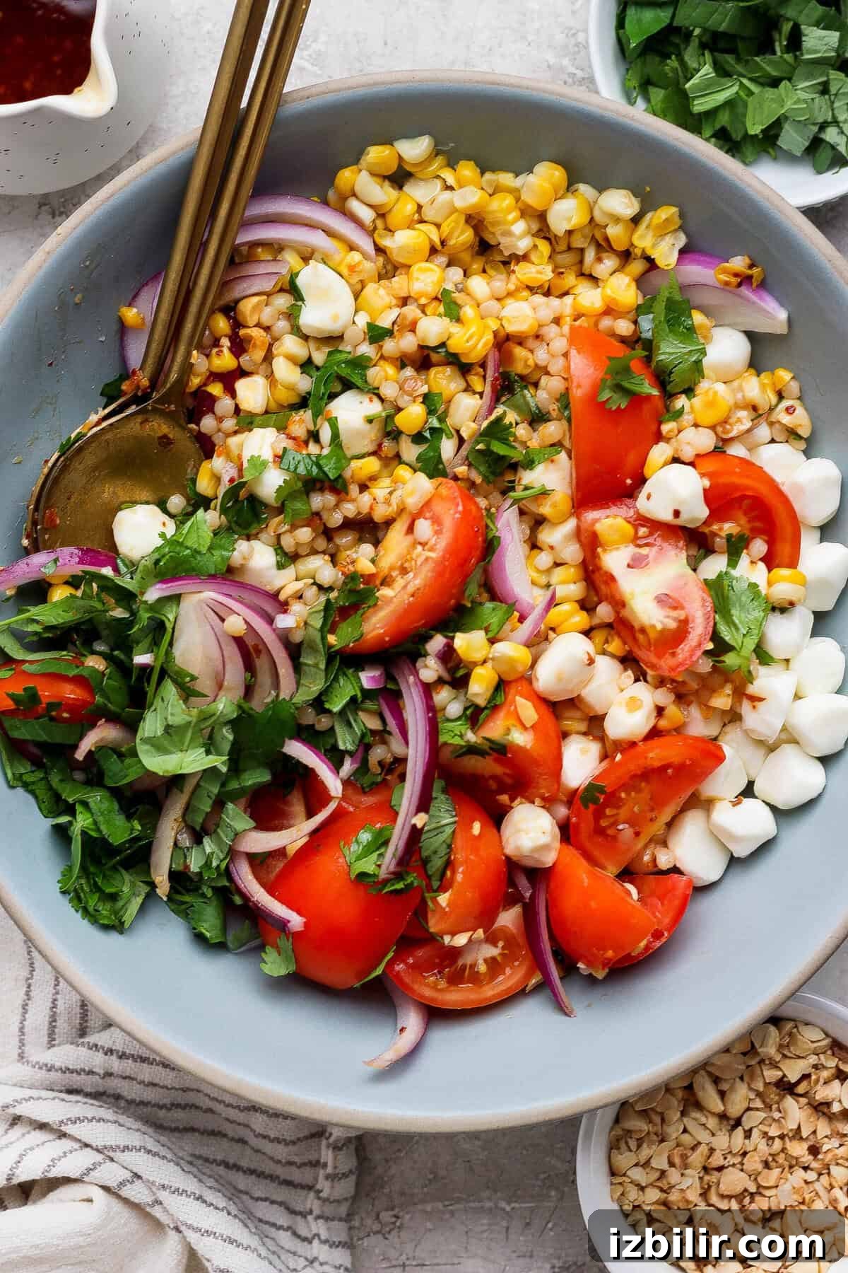 Zesty Summer Corn and Tomato Salad with Chili Crunch Dressing 2 corn tomato salad served in a blue bowl with gold utensils