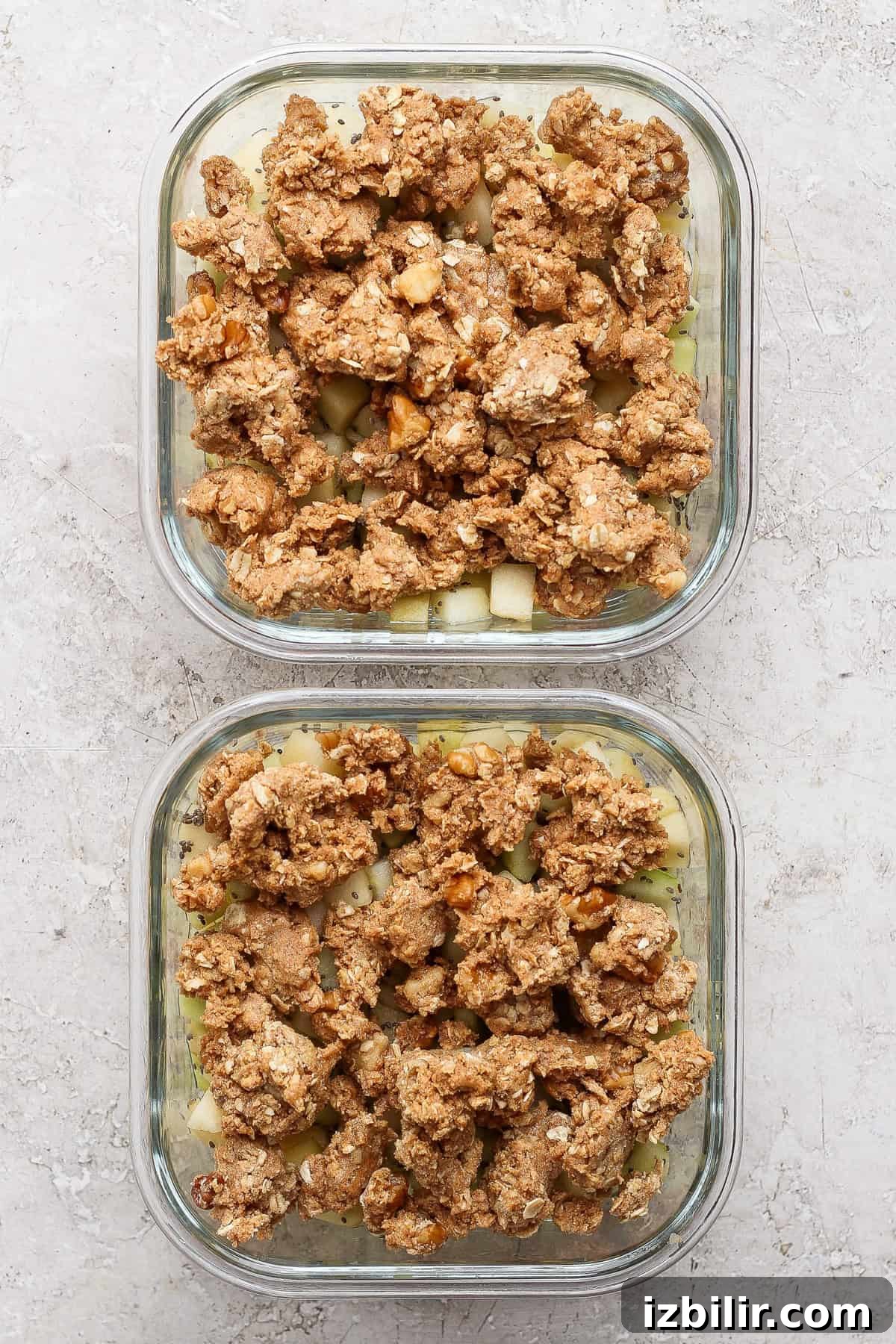 Unbaked protein apple crisp in two square glass meal prep containers.