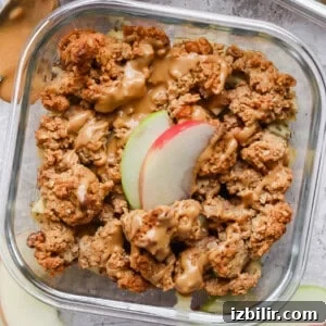 Protein apple crisp in a glass meal prep container topped with nut butter.