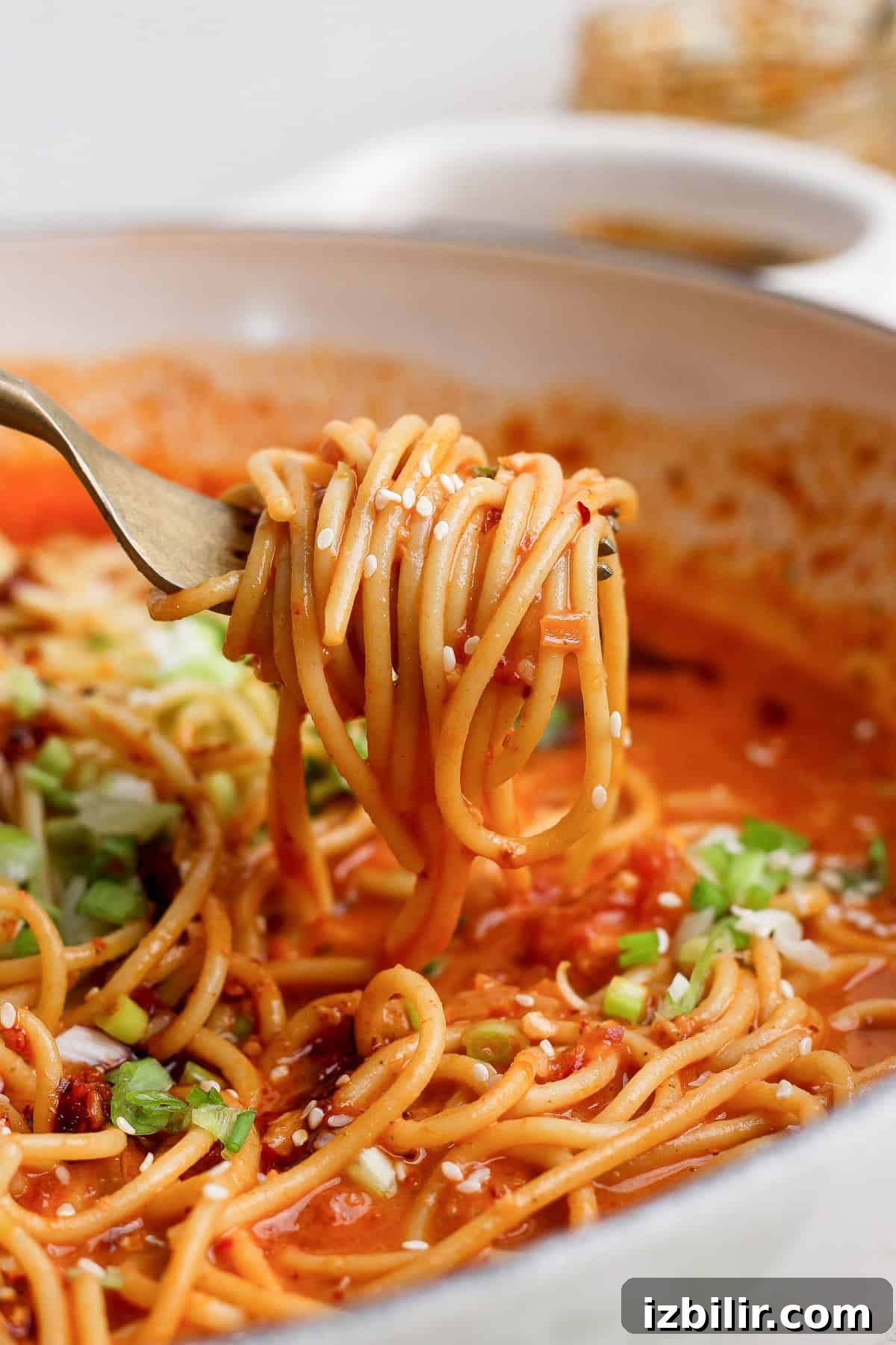 A fork lifting chili crunch pasta coated in smashed tomato sauce.