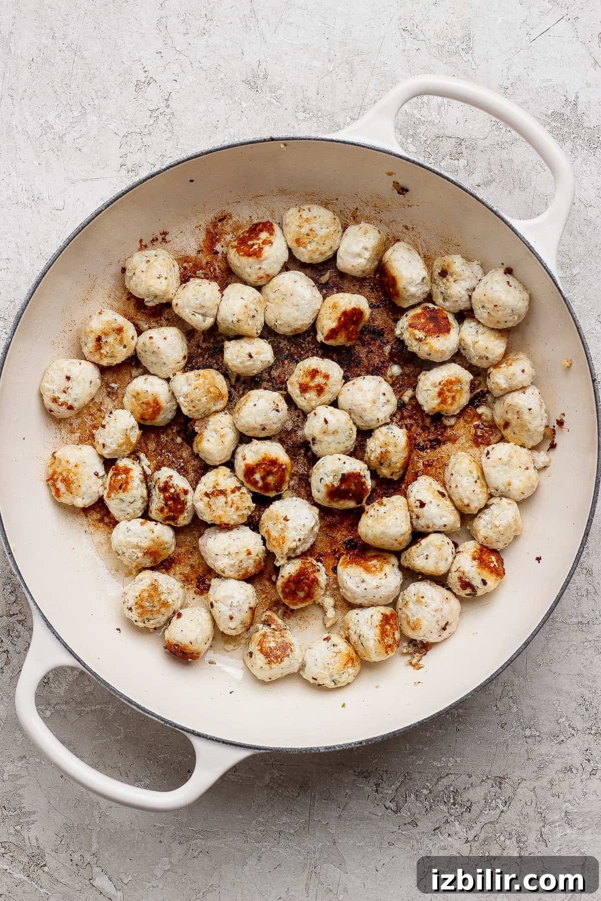 Bite-Sized Cottage Cheese Meatballs with Pasta 4 Browned mini chicken meatballs in a white skillet.
