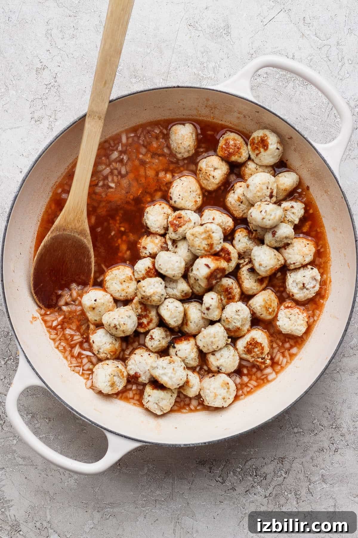 Bite-Sized Cottage Cheese Meatballs with Pasta 6 Mini chicken meatballs simmering in a light tomato pan sauce in a white skillet.