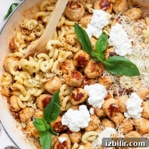 Mini cottage cheese meatballs with elbow pasta, Parmesan, cottage cheese, and fresh basil in a skillet.