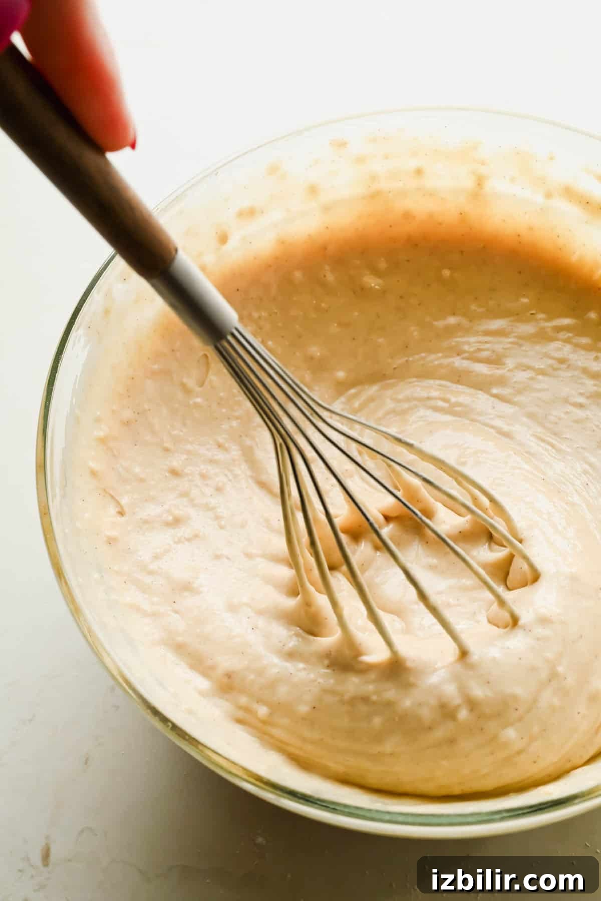 Almond sheet pan pancake batter being whisked in a glass bowl.