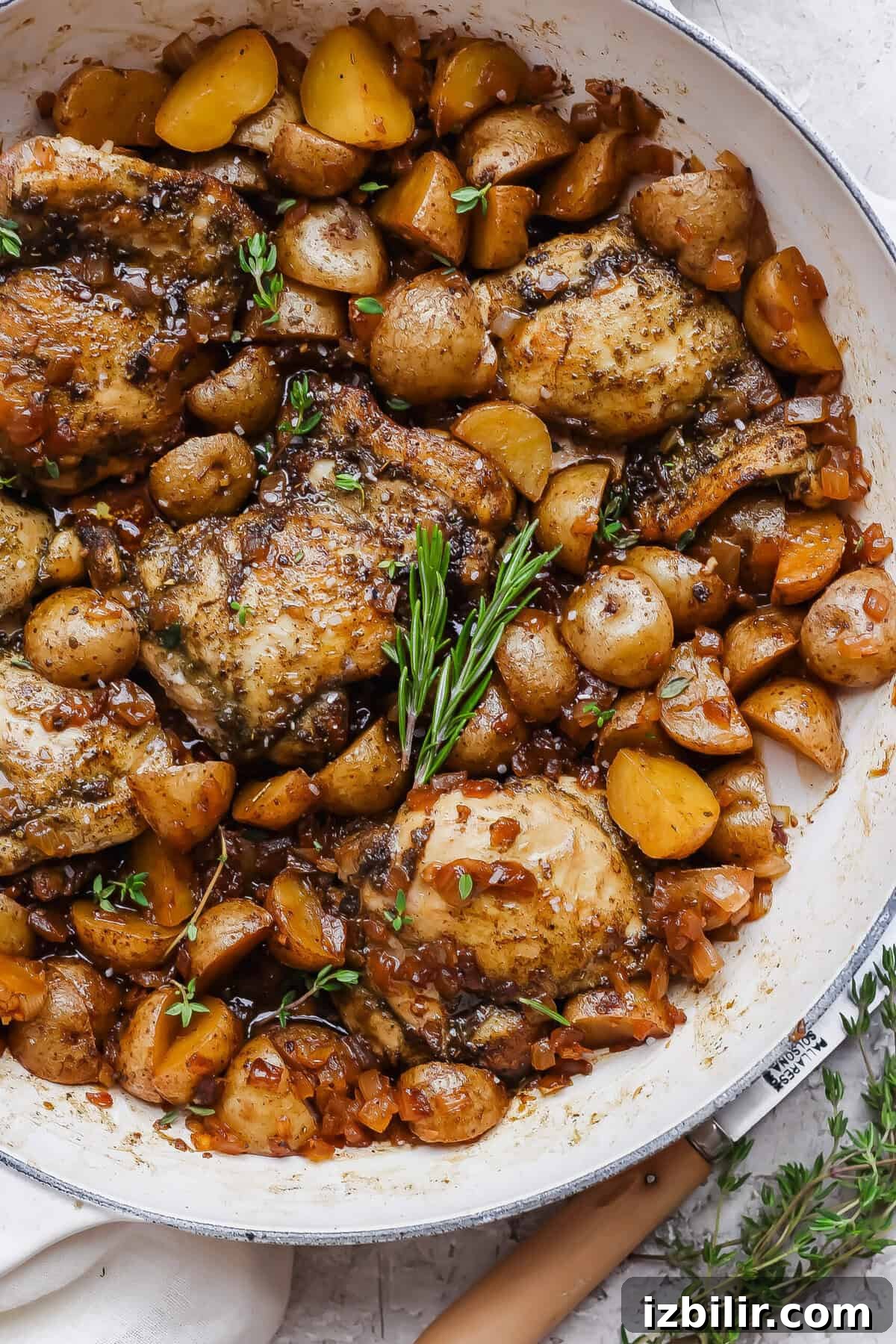 Apple Cider-Glazed Chicken Thighs Recipe 2 Apple cider chicken thighs nestled with baby potatoes and onion in a glossy skillet sauce.