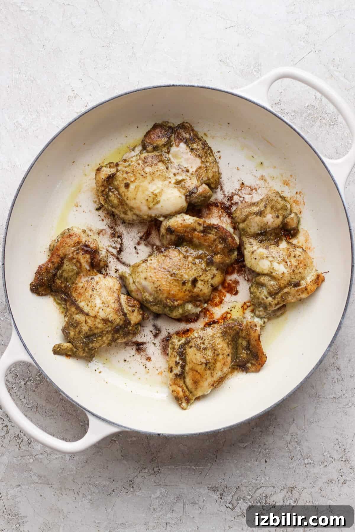 Apple Cider-Glazed Chicken Thighs Recipe 3 Chicken thighs seared until golden brown in a white skillet.