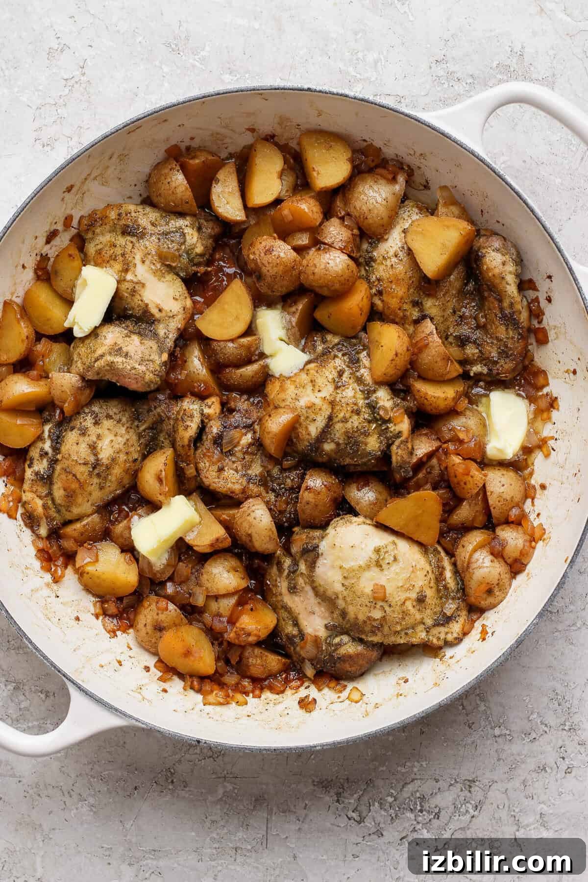 Apple Cider-Glazed Chicken Thighs Recipe 6 Butter melting into the apple cider pan sauce around chicken thighs, potatoes, and onion.