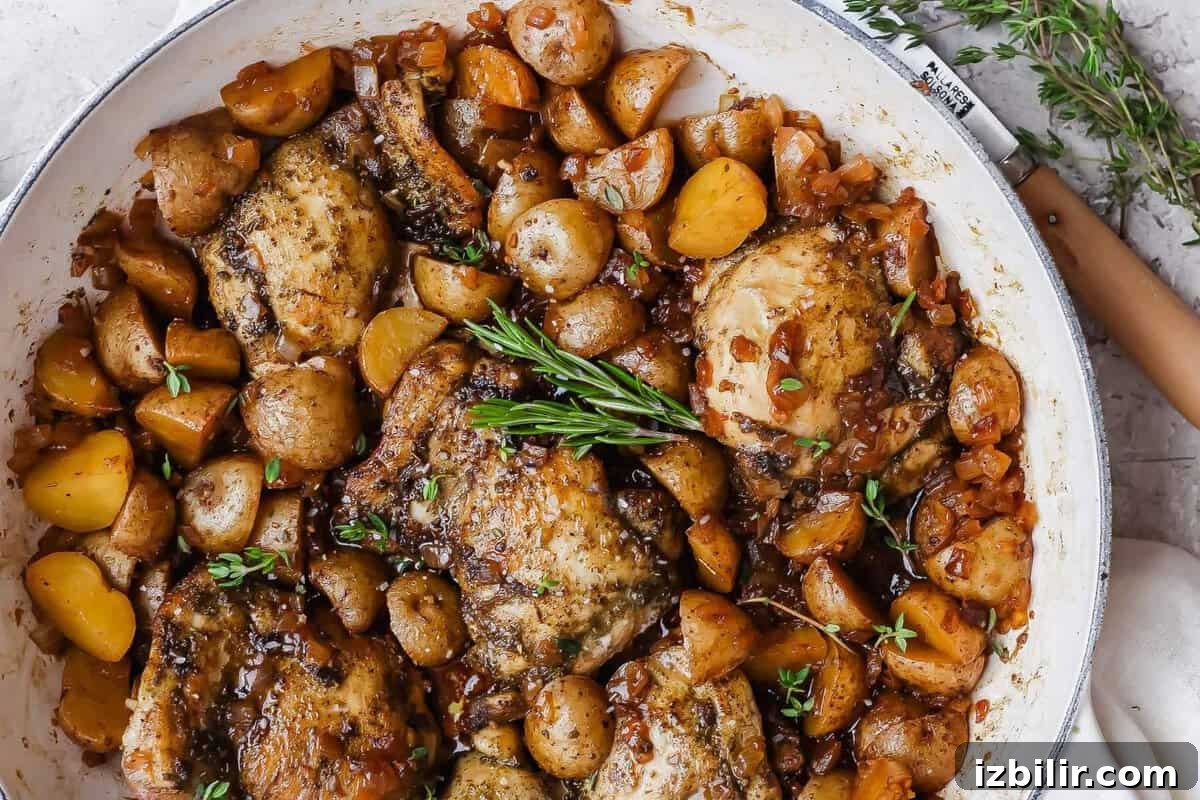Apple Cider-Glazed Chicken Thighs Recipe 8 Apple cider chicken thighs nestled with baby potatoes and onion in a glossy skillet sauce.