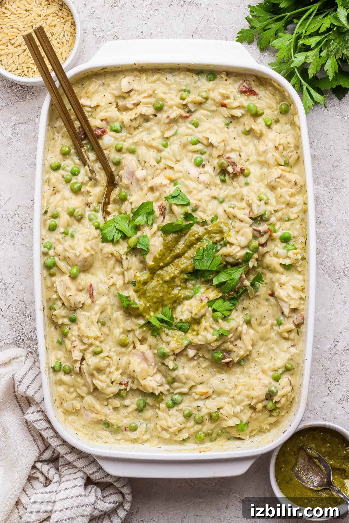 Dump-and-Bake Pesto Chicken Orzo 7 Finished creamy chicken pesto orzo casserole garnished with pesto and fresh parsley.