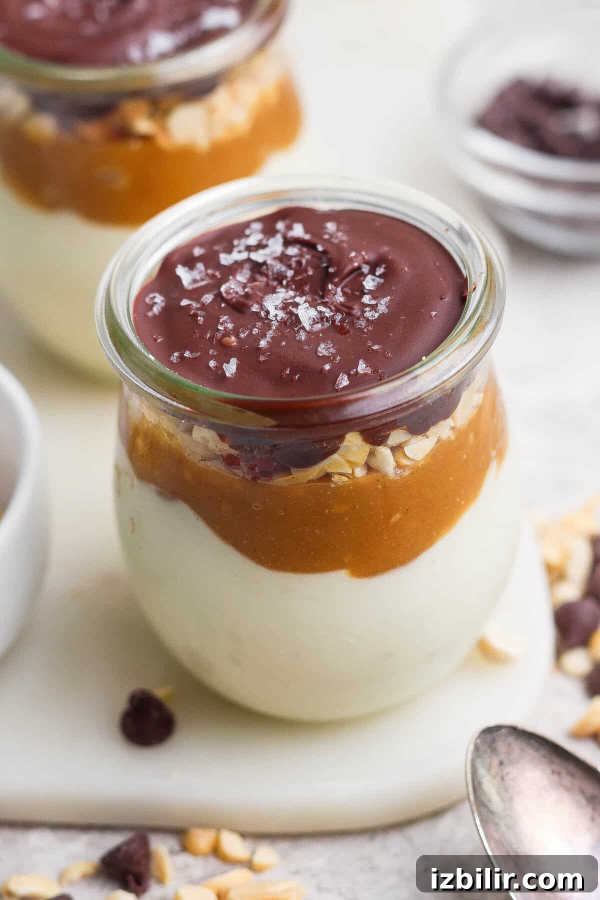 High-Protein Snickers Cheesecake Cups Recipe 3 Individual Snickers cheesecake cup layered with blended cottage cheese, maple peanut butter, salted peanuts, and a glossy chocolate shell.