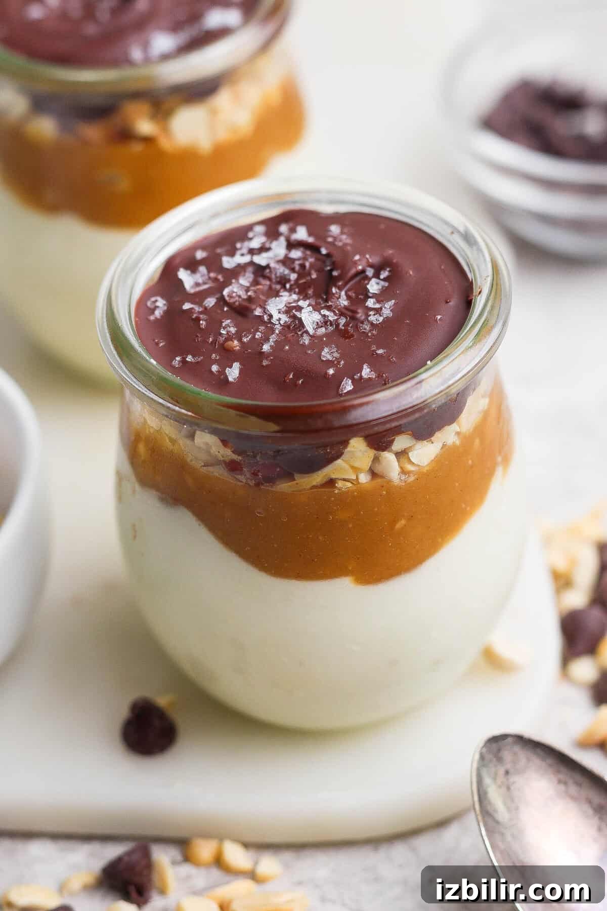 High-Protein Snickers Cheesecake Cups Recipe 8 Individual Snickers cheesecake cup layered with blended cottage cheese, maple peanut butter, salted peanuts, and a glossy chocolate shell.