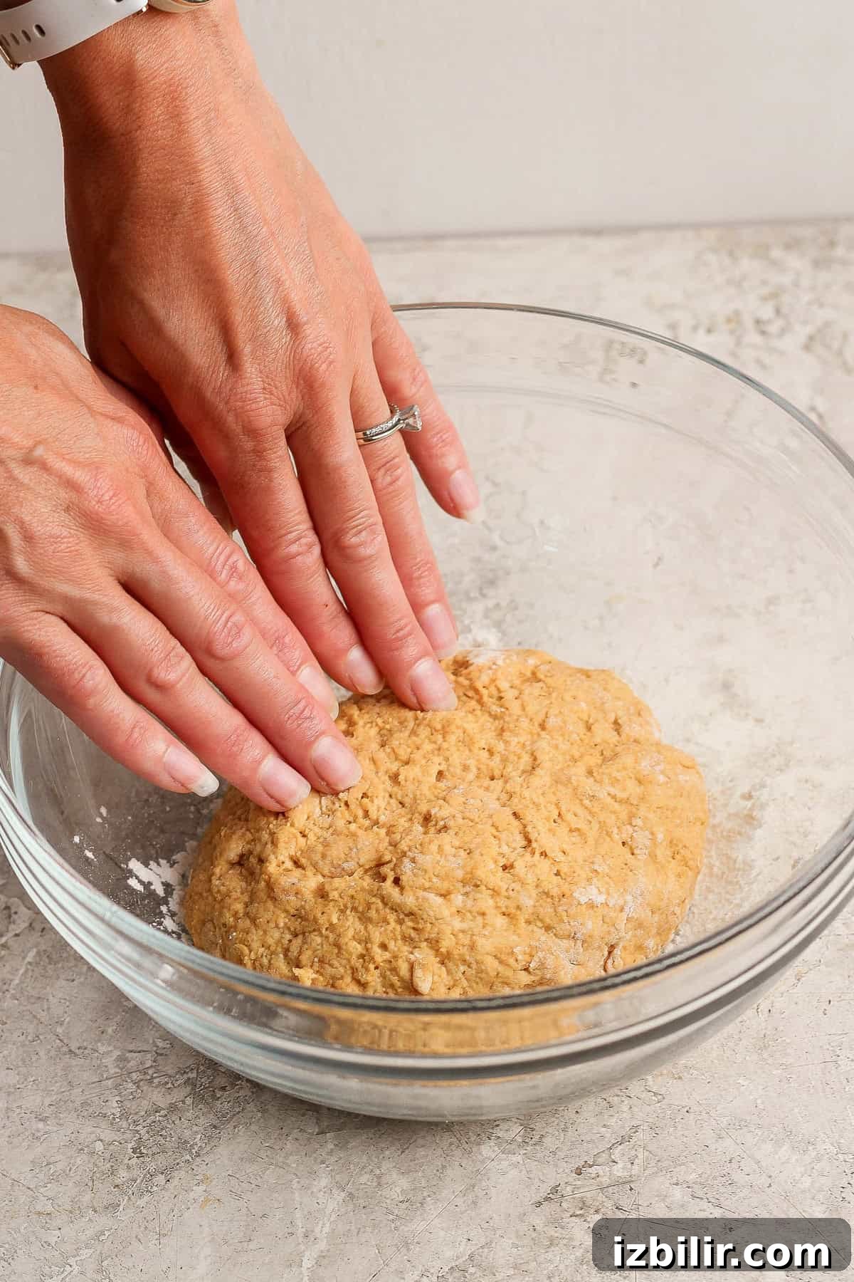 Crispy Cottage Cheese Pumpkin Fritters Recipe 4 Hands gently kneading pumpkin fritter dough in a clear glass mixing bowl.