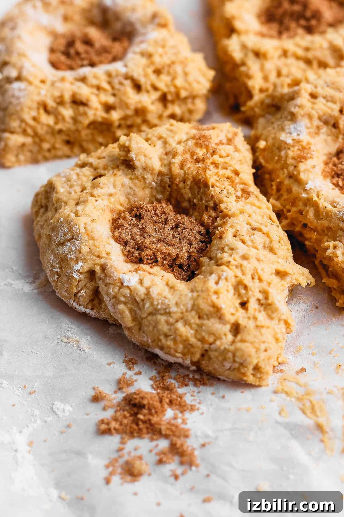 Crispy Cottage Cheese Pumpkin Fritters Recipe 6 Four pieces of pumpkin fritter dough with wells filled with brown sugar and pumpkin pie spice on a floured surface.