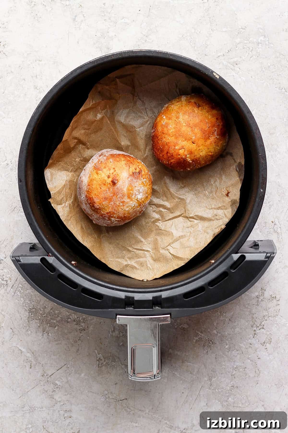 Crispy Cottage Cheese Pumpkin Fritters Recipe 8 Two golden pumpkin fritters resting on parchment paper in an open air fryer basket.
