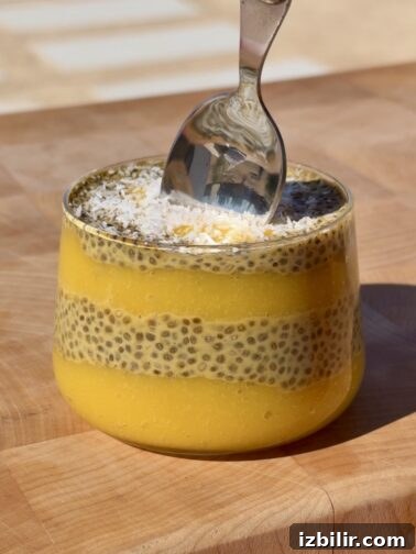Mango turmeric chia pudding in a jar topped with fresh mango and coconut flakes