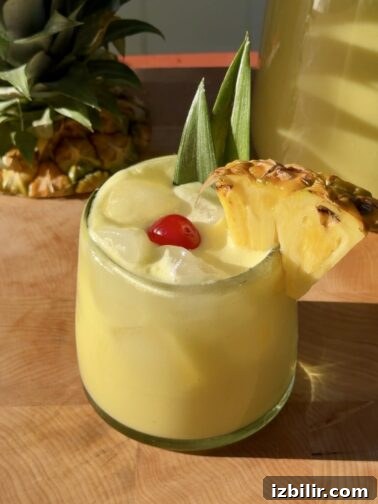 Creamy Piña Colada Agua Fresca in a glass with pineapple garnish